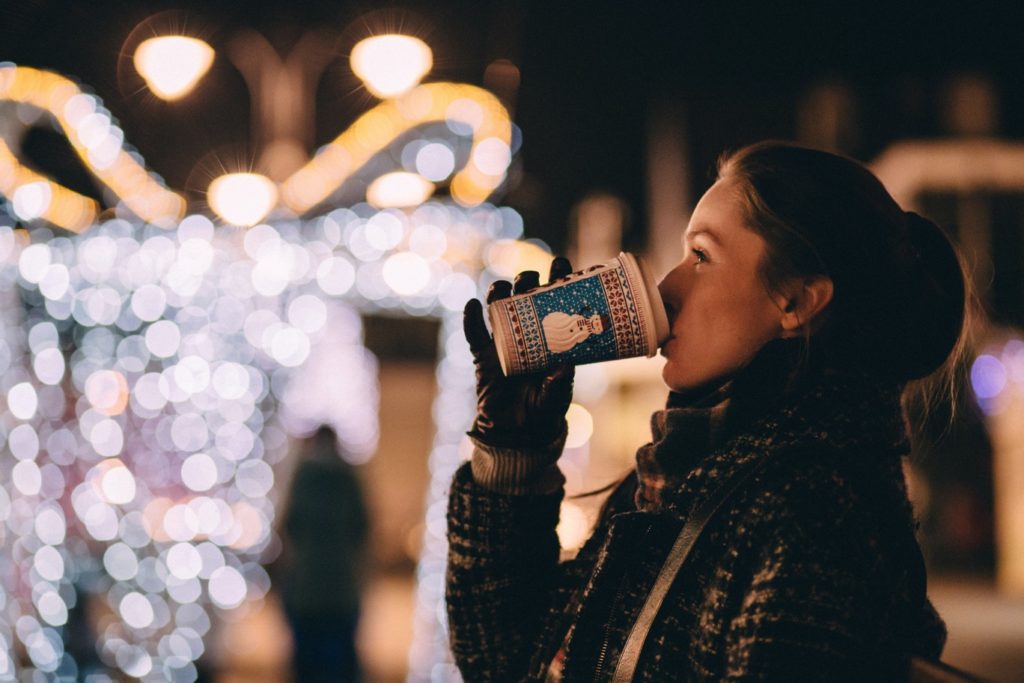 Girl drinking hot beverage at a Christmas market - freestocks-unsplash