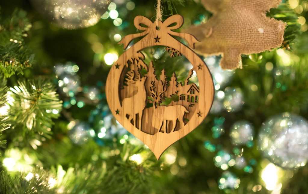 Wooden Christmas ornament on lit Christmas tree - guillaume-bourdages-unsplash